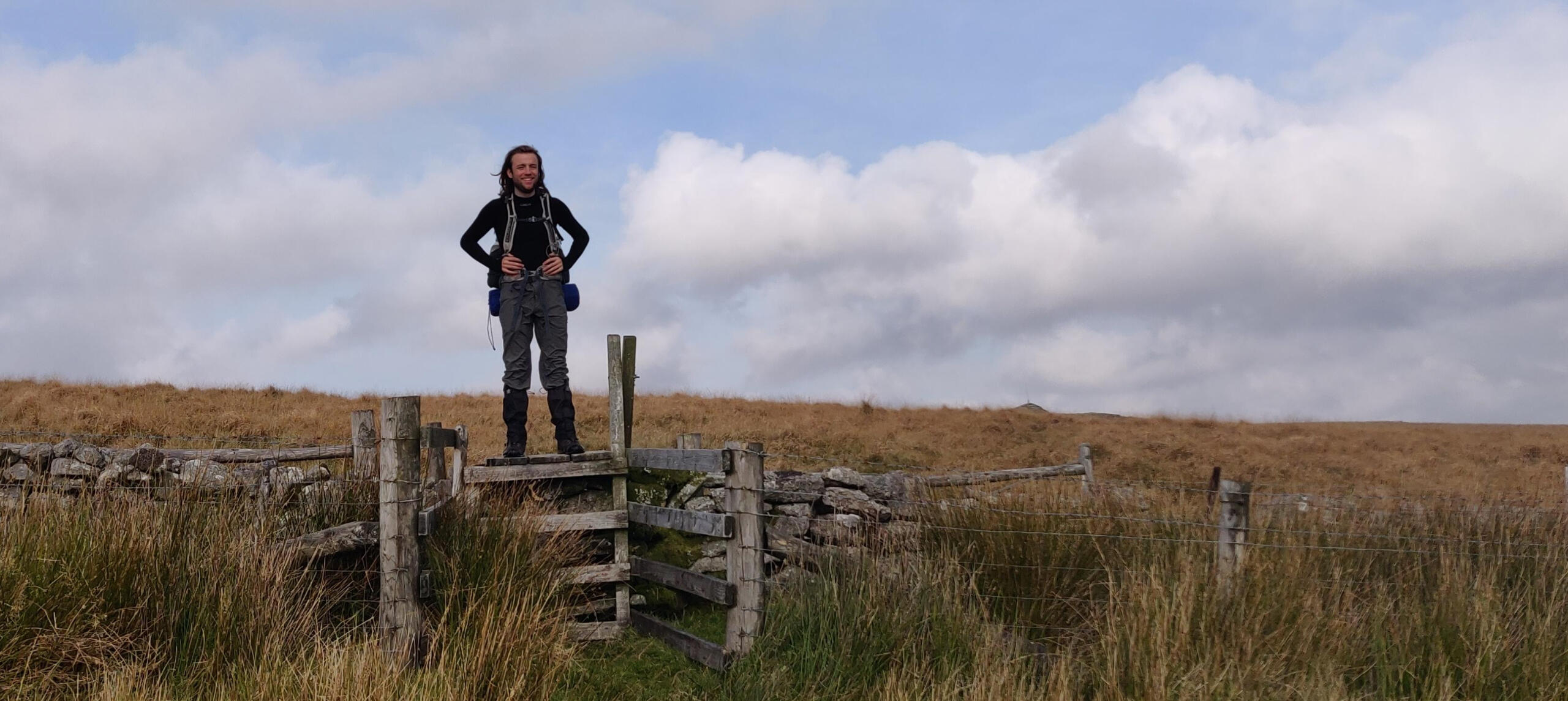 Black and white photo of rock formations in the himalays, with a cyclist below the mountain,